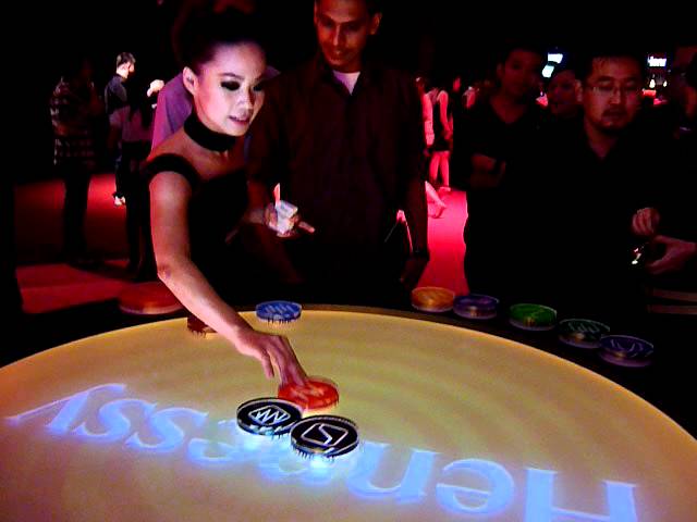 A guest placing a glowing circle on Hennessy's round, illuminated music surface